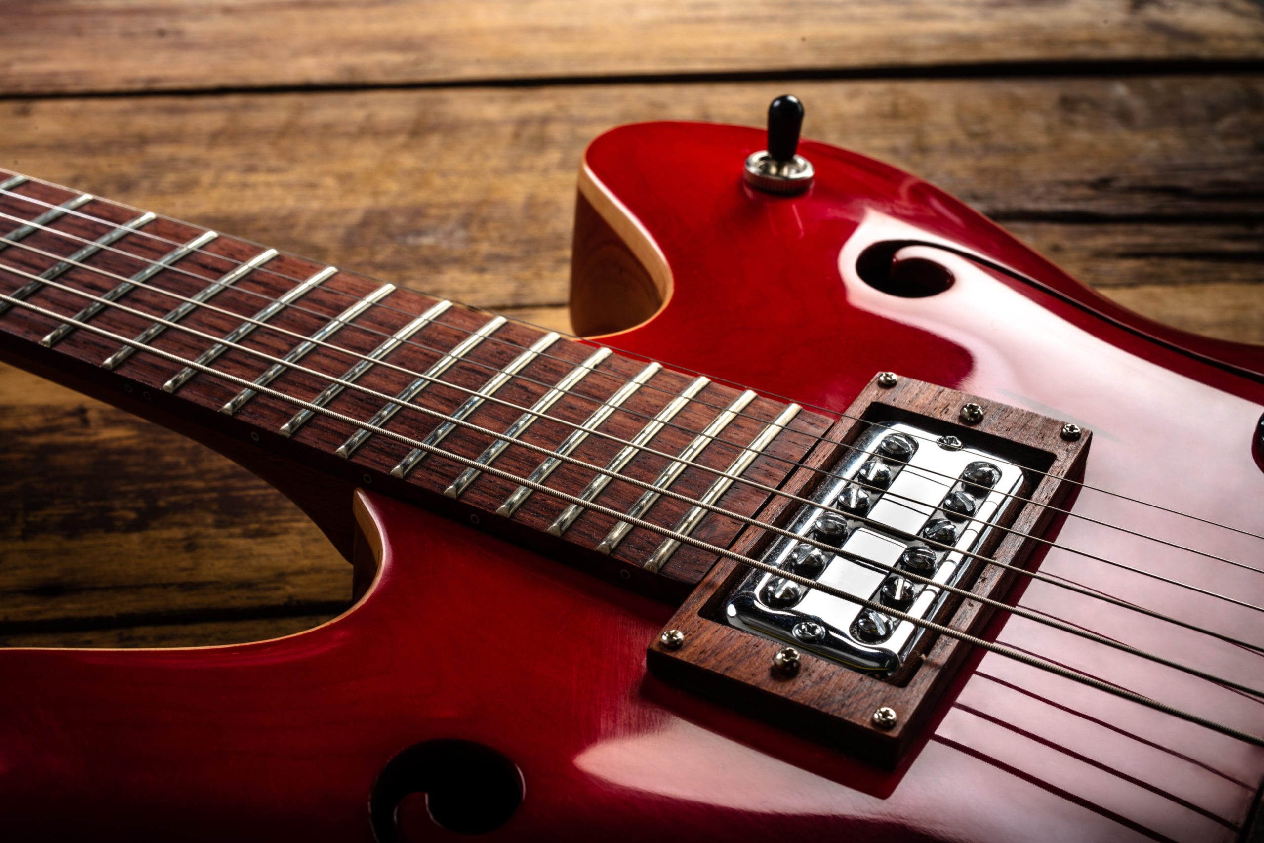 The red guitar that was laid on the floor of an old wooden plate.
